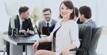 successful female accountant smiling while sitting at a table with other accountants