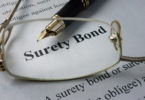 eye glasses laying on top of surety bond document with pen