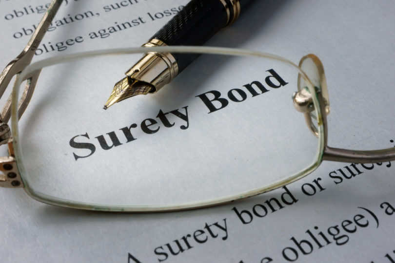 eye glasses laying on top of surety bond document with pen